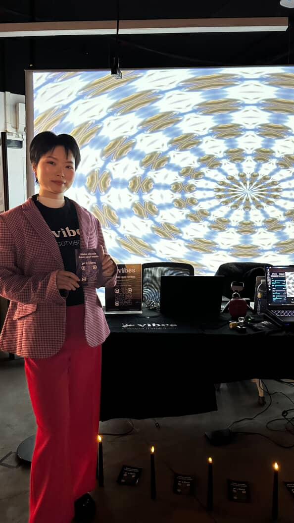 Yiting Liu presenting a Vibes demo table with live AI visuals projected behind her